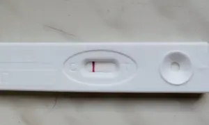 Blada kreska na teście ciążowym, widoczna przy literze "C", sugeruje wynik negatywny.
