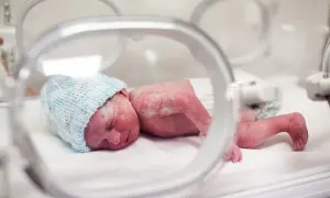 Maleńki noworodek, dziecko urodzone w 20 tygodniu ciąży, w inkubatorze, w niebieskiej czapeczce.