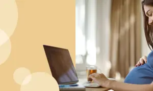 Kobieta w ciąży przy laptopie, która uśmiecha się, dotykając brzucha. Dowiaduje się, jak liczyć ruchy dziecka.