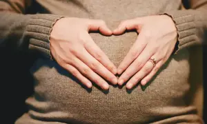 Dłonie tworzą serce na brzuchu ciężarnej. Od kiedy pojawiają się skurcze Braxtona Hicksa?