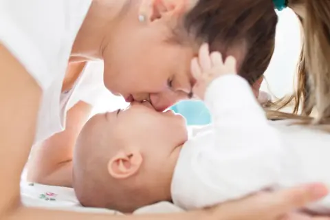 Czuły pocałunek mamy dla jej 5-miesięcznego dziecka.