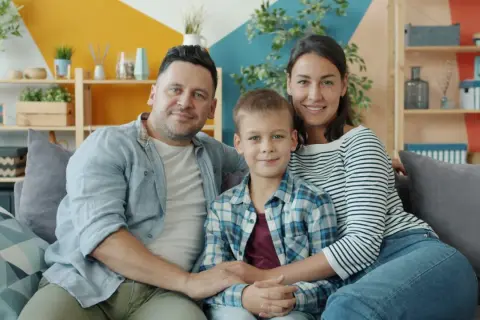 Szczęśliwa rodzina: tata, mama i syn siedzą na kanapie. Choć nie da się określić, ile kosztuje dziecko, miłość i radość są bezcenne.