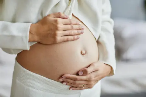 Delikatne dotknięcie brzucha, by poczuć, jak pobudzić ruchy dziecka w brzuchu. Czułe dłonie przyszłej mamy.