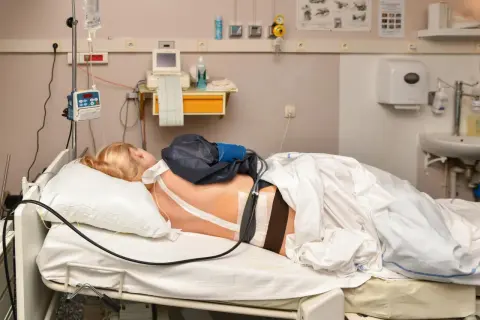 Kobieta w łóżku szpitalnym, przygotowana do porodu. Znieczulenie do porodu podawane przez pompę infuzyjną.