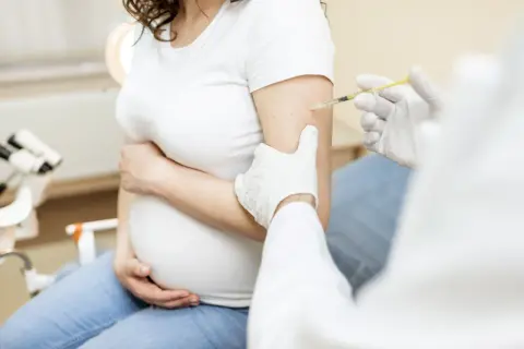 Szczepienie RSV w ciąży chroni matkę i dziecko. Lekarz podaje zastrzyk w ramię ciężarnej kobiety.
