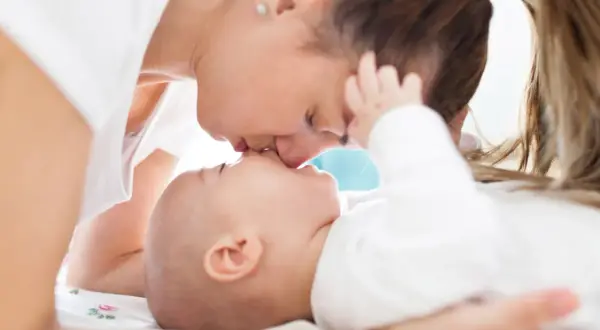 Czuły pocałunek mamy dla jej 5-miesięcznego dziecka.