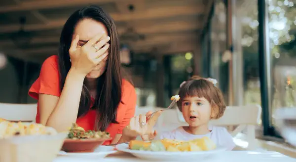 Zmęczona mama zakrywa twarz, gdy jej bananowe dzieci odmawiają jedzenia.