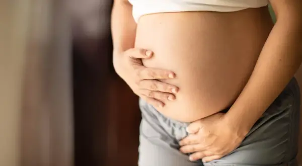 Brzuch ciężarnej kobiety, która zastanawia się, czy dziecko w brzuchu robi kupę.