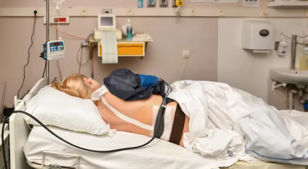 Kobieta w łóżku szpitalnym, przygotowana do porodu. Znieczulenie do porodu podawane przez pompę infuzyjną.