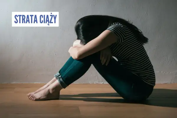 Smutna kobieta siedzi skulona na podłodze, przeżywając stratę ciąży.