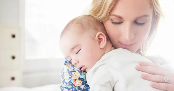 Samotna matka tuli śpiące dziecko. Delikatne światło otula ich spokój.