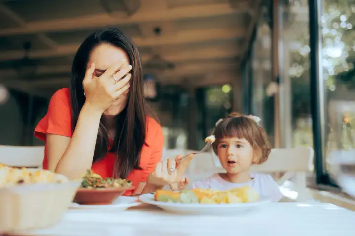 Zmęczona mama zakrywa twarz, gdy jej bananowe dzieci odmawiają jedzenia.